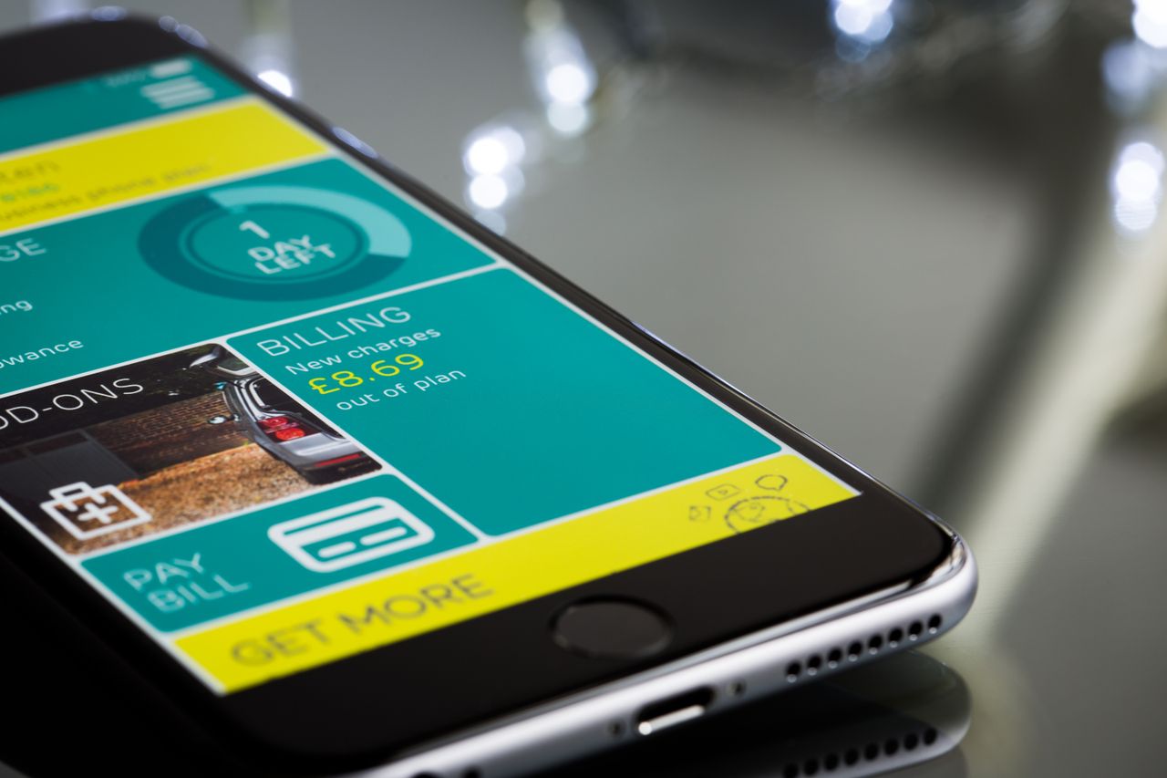Services Close-up of a smartphone displaying a billing app interface on a reflective surface.