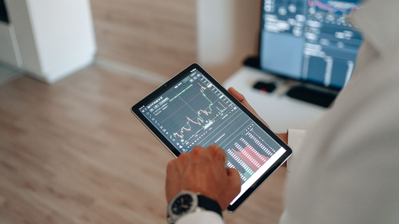 Services Close-up of hands using a tablet for online trading and market analysis.